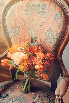 Cozy retro vintage furniture interior design catle room with wicked wooden furniture in red brown colours. Artificial flowers bouquet on chair. Beauty and simplicity, no people.