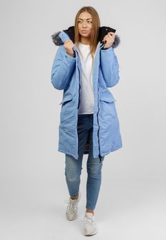 young woman in winter clothes on white background. Photo concept for advertising a down jacket.