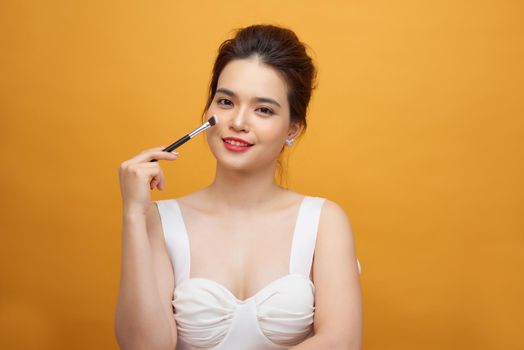 Woman applying make up with brush, isolated. Beauty procedures