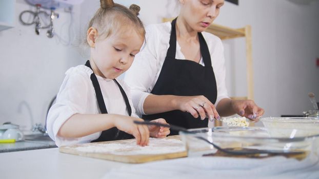 Mother and her little daughter forms cottage cheese pancakes, close up