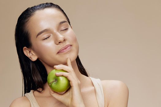 woman green apple near face health beige background. High quality photo