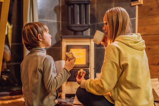 Mom and son spend time by the fireplace in Glamping. Rest in the mountains in Glamping. Cozy fireplace in a mountain house.