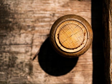 Old round wooden doorknob with light shadow. Door handle. Round form. Wood material. Sunlight. Aging process. background image. Carpentry product. The work of a carpenter.
