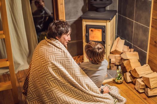 Dad and son spend time by the fireplace in Glamping. Rest in the mountains in Glamping. Cozy fireplace in a mountain house.