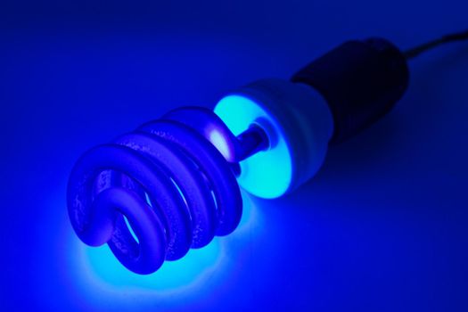 compact UV - ultraviolet CCFL - Cold Cathode Fluorescent Lamp on white surface, turned on