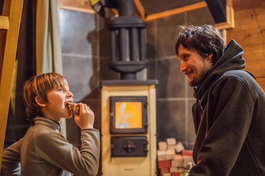 Dad and son spend time by the fireplace in Glamping. Rest in the mountains in Glamping. Cozy fireplace in a mountain house.