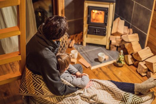 Dad and son spend time by the fireplace in Glamping. Rest in the mountains in Glamping. Cozy fireplace in a mountain house.