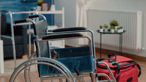 Close up of wheelchair for transportation support and medical bag on floor of nursing home. Chair used for accessibility and handbag filled with equipment and tools for healthcare.