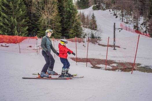 Boy learning to ski, training and listening to his ski instructor on the slope in winter.