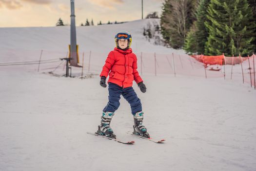 Child skiing in mountains. Active toddler kid with safety helmet, goggles and poles. Ski race for young children. Winter sport for family. Kids ski lesson in alpine school. Little skier racing in snow.