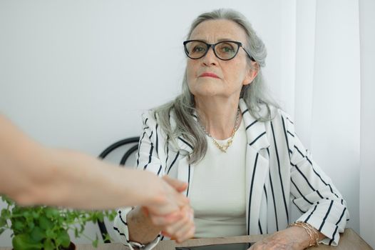 Mature businesswoman is leading an interview with new colleague and shaking their hand at the end. Business people concept.