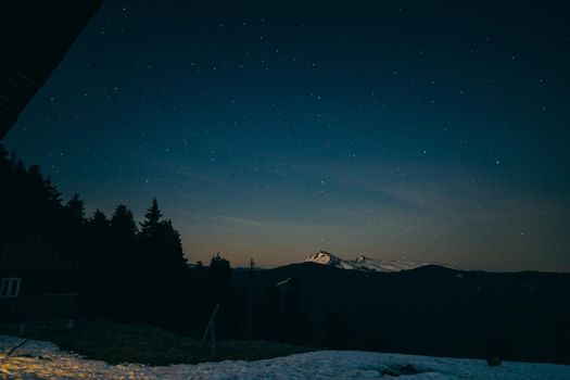 Snowy meadow, snowy mountains and stars in the background. High quality photo
