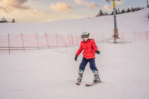 Child skiing in mountains. Active toddler kid with safety helmet, goggles and poles. Ski race for young children. Winter sport for family. Kids ski lesson in alpine school. Little skier racing in snow.