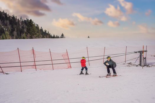 Boy learning to ski, training and listening to his ski instructor on the slope in winter.