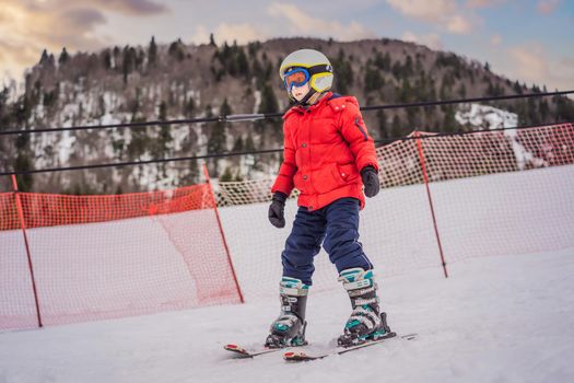 Child skiing in mountains. Active toddler kid with safety helmet, goggles and poles. Ski race for young children. Winter sport for family. Kids ski lesson in alpine school. Little skier racing in snow.