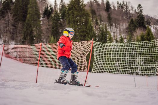 Child skiing in mountains. Active toddler kid with safety helmet, goggles and poles. Ski race for young children. Winter sport for family. Kids ski lesson in alpine school. Little skier racing in snow.