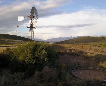 Windmill and water pump in dry landscape