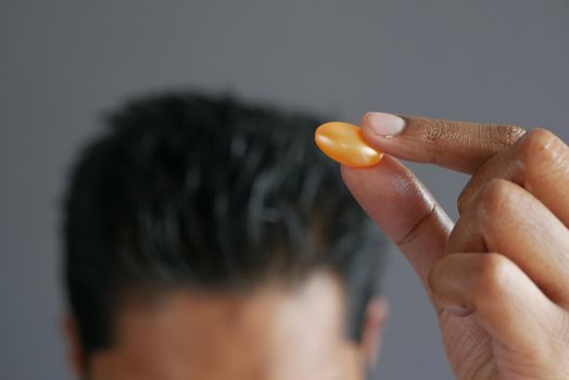 men applying capsule oil on hair .