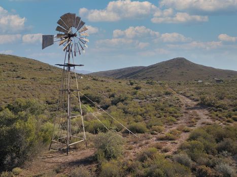 Windmill and water pump in dry landscape