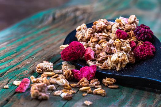 Cereal mixtures with strawberries, blackberries and freeze-dried raspberries spilled on a board.