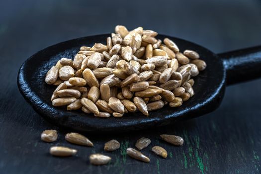 Sunflower seeds in macro in a black wooden spoon