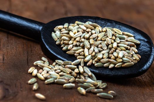 small stack of rye seeds in macro on old board