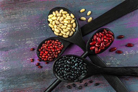 White, red and black beans - high view on old wooden board