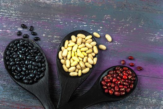 White, red and black beans - high view on old wooden board