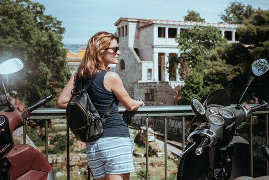 Beautiful girl walking along the street of an old European town with a film camera in her hand. Portrait of a tourist girl walking on the street background