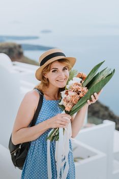 Beautiful girl walking along the street of Santorini island, an old European town, Greece. Portrait of a tourist girl walking on the street background