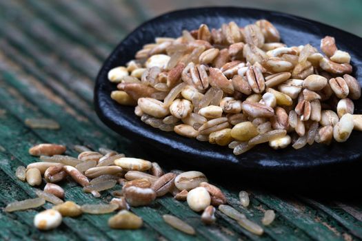 spelt,barley,wheat,oatsrice mixed in an inverted spoon