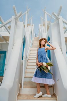 Beautiful girl walking along the street of Santorini island, an old European town, Greece. Portrait of a tourist girl walking on the street background