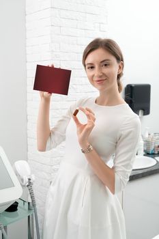 Cosmetologist dermatologist holds a package with drugs for facial rejuvenation. A female doctor in office shows treatment options.