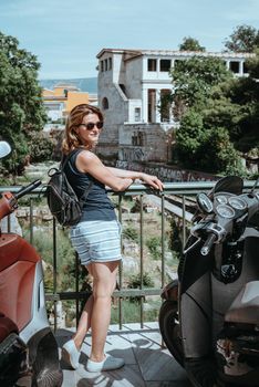 Beautiful girl walking along the street of an old European town with a film camera in her hand. Portrait of a tourist girl walking on the street background