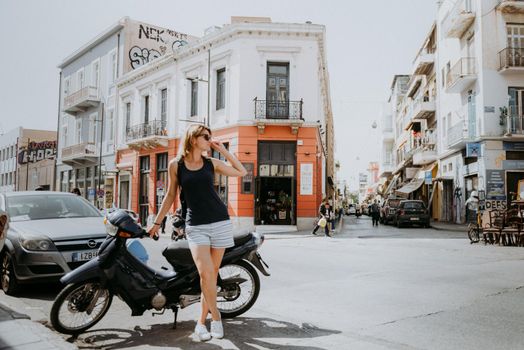 Beautiful girl walking along the street of an old European town with a film camera in her hand. Portrait of a tourist girl walking on the street background