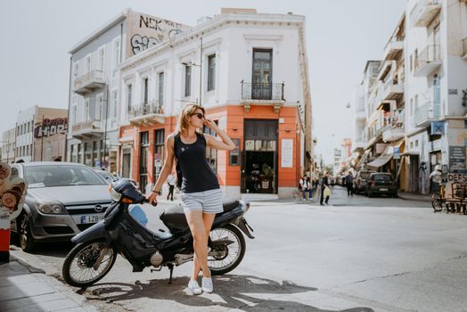 Beautiful girl walking along the street of an old European town with a film camera in her hand. Portrait of a tourist girl walking on the street background