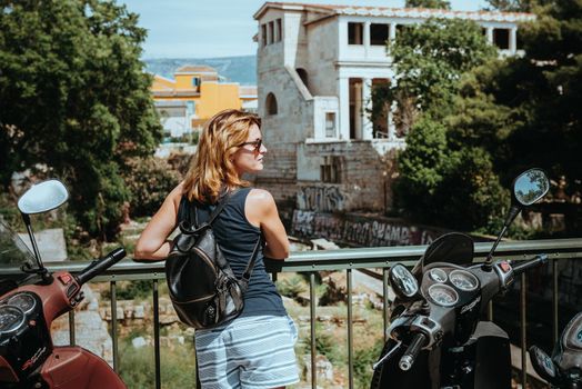 Beautiful girl walking along the street of an old European town with a film camera in her hand. Portrait of a tourist girl walking on the street background