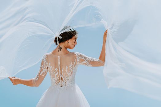 Romantic beautiful bride in white dress posing on terrace with sea and mountains in background