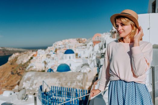 Santorini travel tourist woman on vacation in Oia walking. Girl visiting the famous white village with the mediterranean sea and blue domes. Europe summer destination. Beautiful Girl on the background of the Island of Santorini