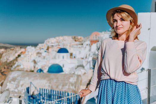 Santorini travel tourist woman on vacation in Oia walking. Girl visiting the famous white village with the mediterranean sea and blue domes. Europe summer destination. Beautiful Girl on the background of the Island of Santorini