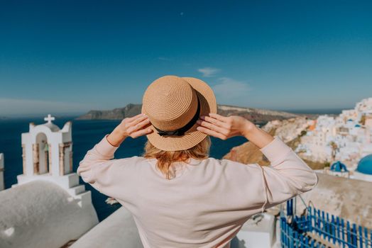 Santorini travel tourist woman on vacation in Oia walking. Girl visiting the famous white village with the mediterranean sea and blue domes. Europe summer destination. Beautiful Girl on the background of the Island of Santorini