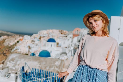 Santorini travel tourist woman on vacation in Oia walking. Girl visiting the famous white village with the mediterranean sea and blue domes. Europe summer destination. Beautiful Girl on the background of the Island of Santorini