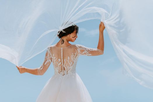 Romantic beautiful bride in white dress posing on terrace with sea and mountains in background