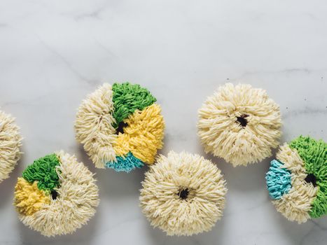 Shag donuts on white marble background. Unusual trendy colorful donuts with vanilla buttercream. Copy space. Top view or flat lay.