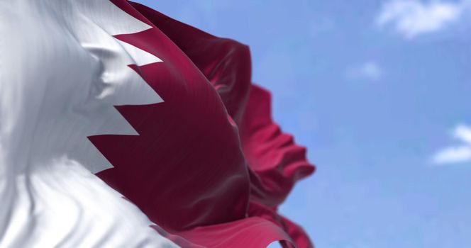 Detail of the national flag of Qatar waving in the wind on a clear day. Western asia country. Patriotism. Selective focus.