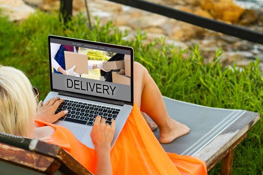 female hands on laptop computer with parcel delivery application on screen at table in cafe.