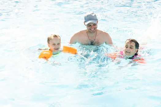 Happy family playing in swimming pool. Summer vacation concept.