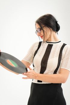 Studio photo of middle aged woman starting getting grey-haired wearing black and white clothes with vinyl record in hands on white background, middle age sexy lady, happy life concept.