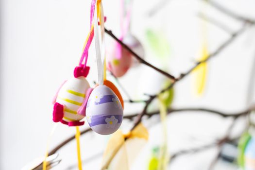 Tree branches decorated with Easter eggs and feathers in a glass vase