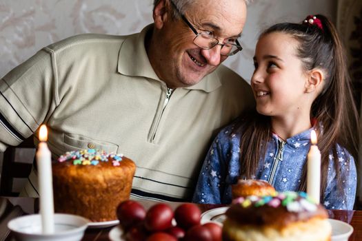 grandfather and granddaughter at a festive table to celebrate Easter.